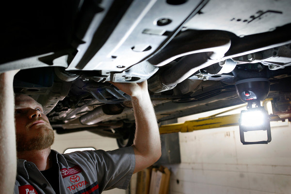 Car mechanic using LED work light under vehicle