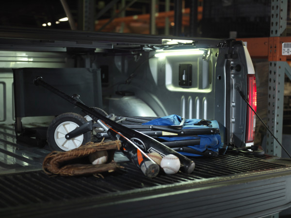 Truck bed lighting kit shining light on baseball equipment at night