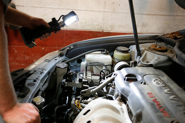 Mechanic using LED work light bz401-5 to look under car hood